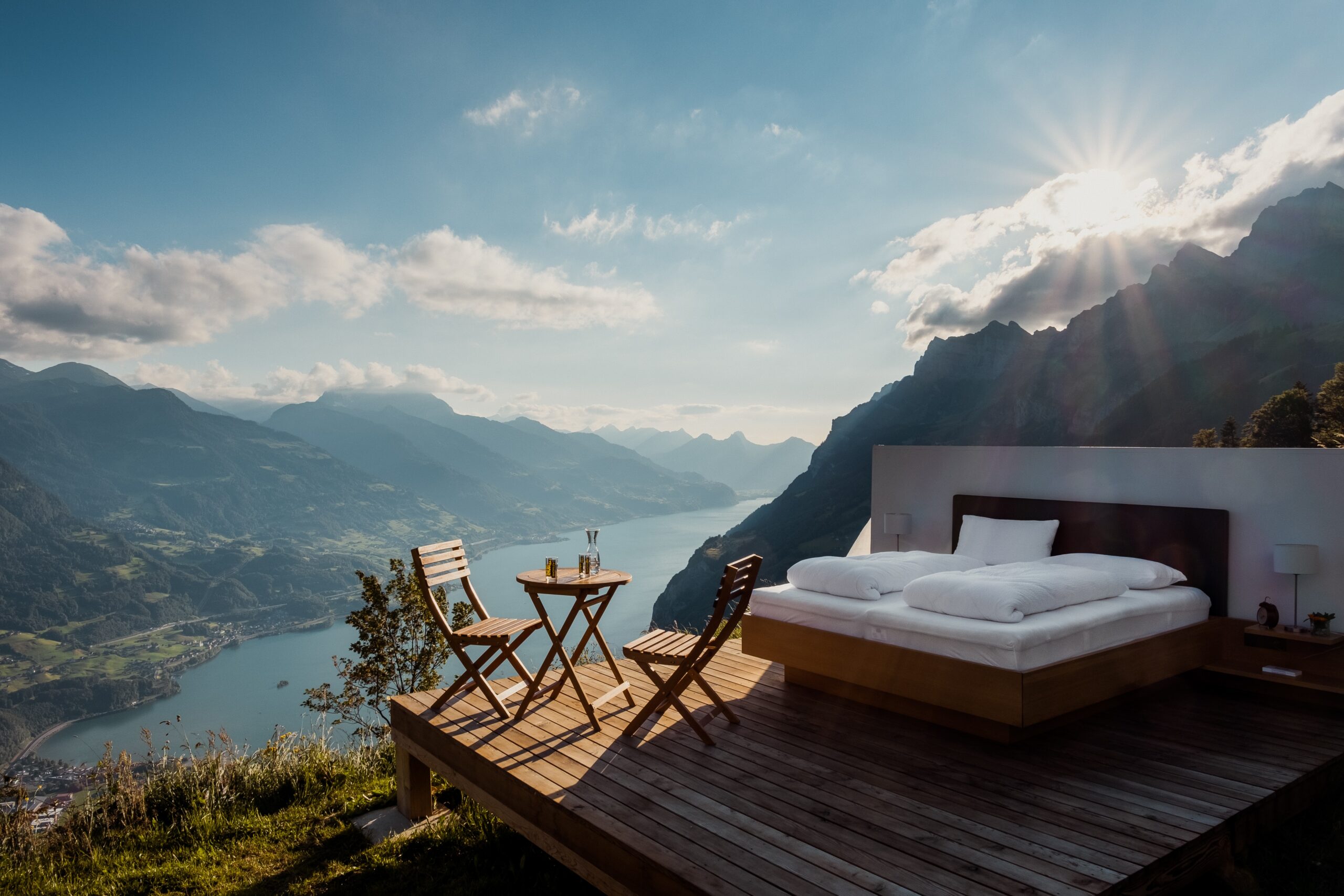 bedroom with chairs and desk on a mountain with sun rising behind clouds.